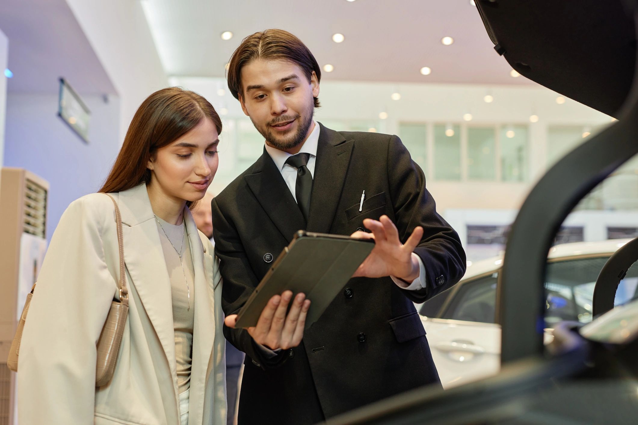 Auto dealer showing financing details to a customer on a tablet