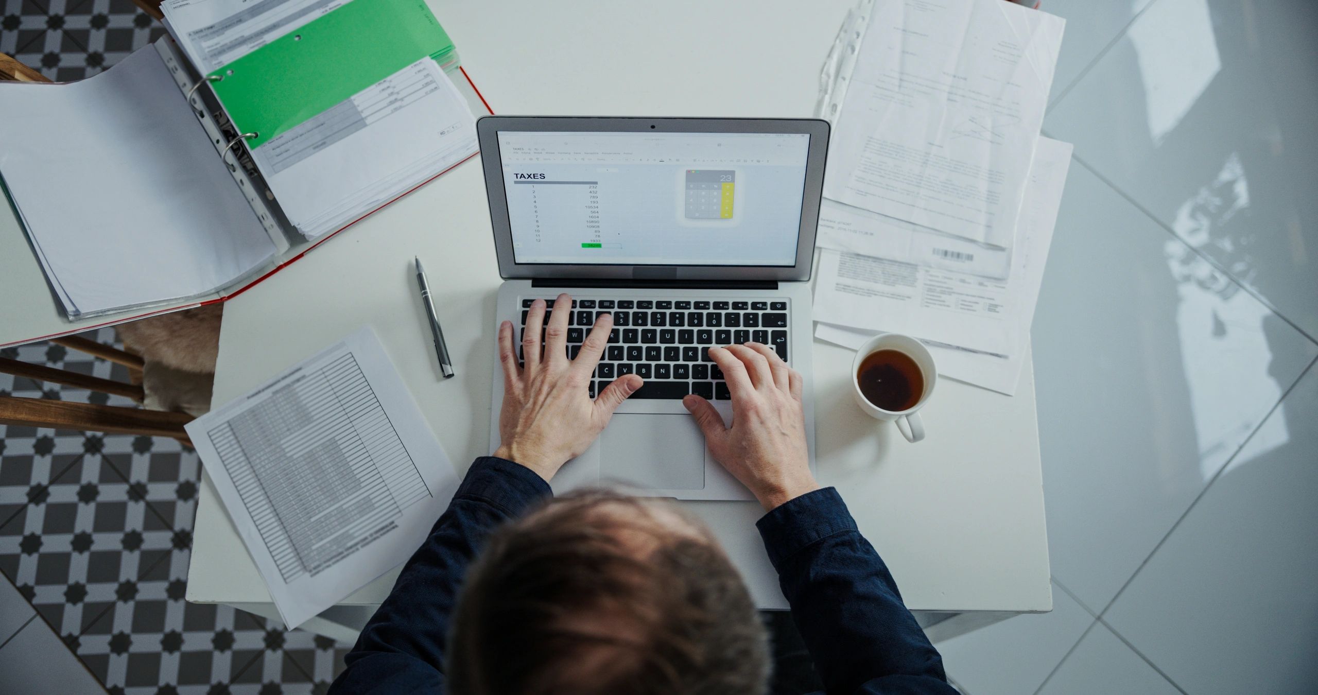 Hands using a laptop and paperwork to review payment calculations